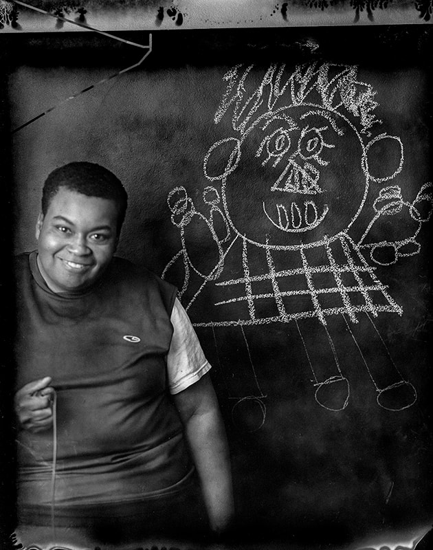 plack and white photo of a woman taking self-portrait in front of her chalk drawing
