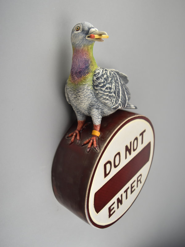 Ceramic sculpture of a pigeon sitting on a "Do Not Enter" sign.