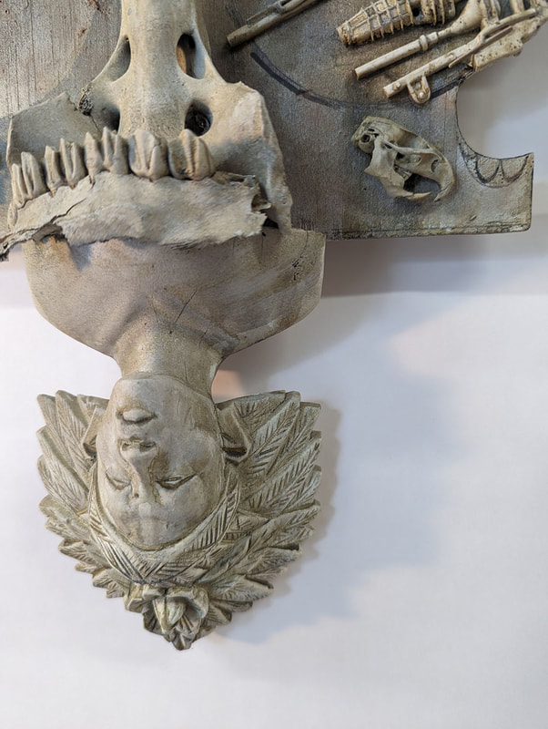 A detail of a sculpture showing an upside down with a head dress of leaves