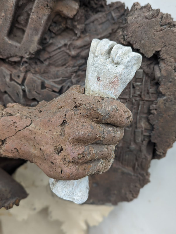 A detail of a sculpture showing a hand grasping a bone