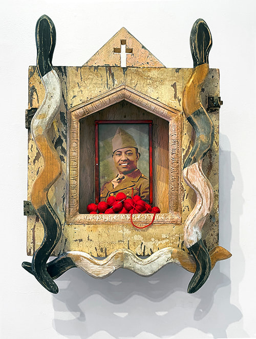 3D Artwork  including carved wood snakes, a portrait of a soldier and red balls of thread