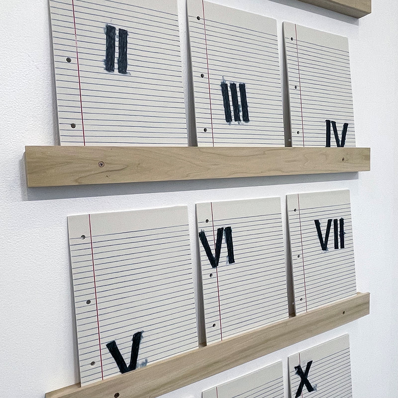 sculpture made of sheets of porcelain that look like sheets on notebook paper with roman numerals drawn on them