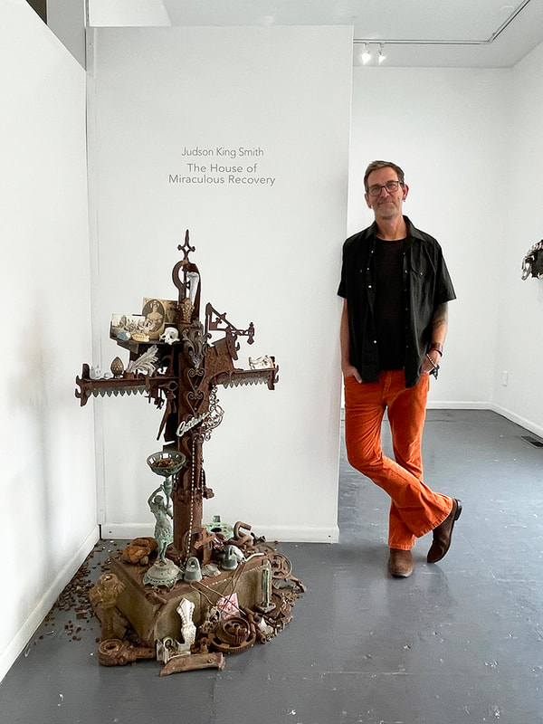 Artist Judson King Smith and a cross shaped sculpture made of many objects