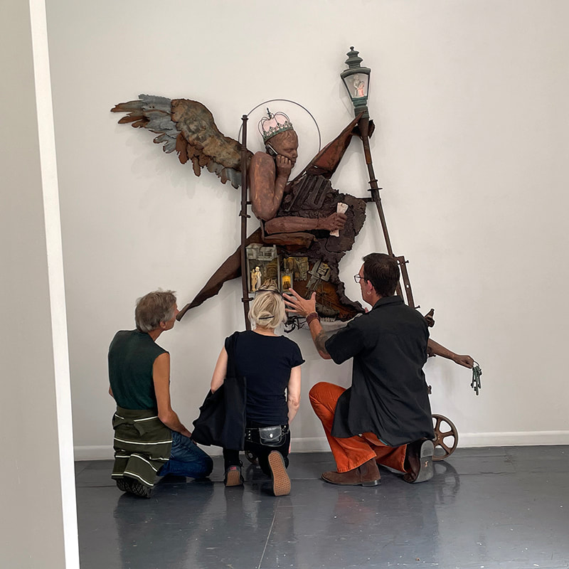 Artist Judson King Smith shows viewers a sculpture of a winged person made of many objects