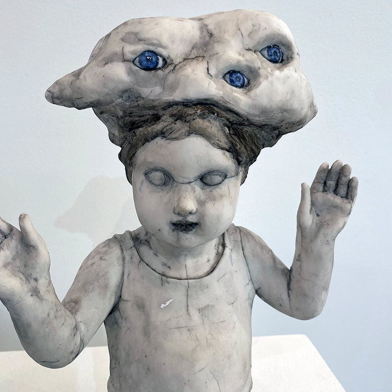 sculpture of a child holding up their hands with a cloud-like shape with many eyes sitting on their head 