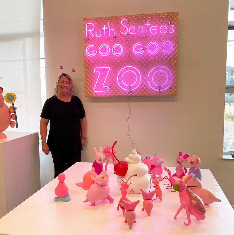 woman with sculpture of fanciful pink creatures worshipping a whipped cream and cherry sculpture