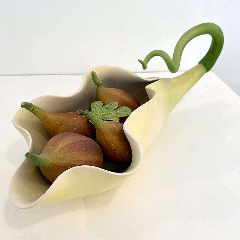 sculpture of four figs in a calla lilly shaped blossonmwith a curly stem