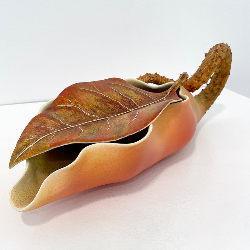 porcelain sculputre of two leaves, one on top of the other, the bottom one has a bumpy curling stem