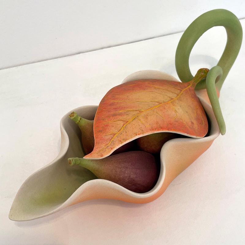 ceramic sculpture og figs laying in a flower blossom shape and covered by a leaf shape