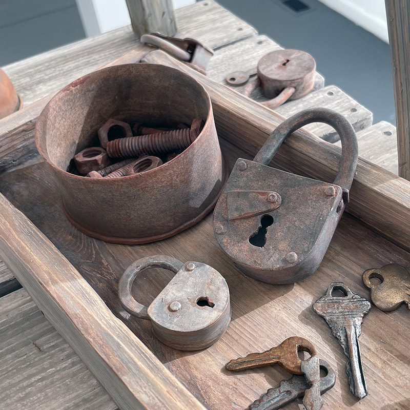 porcelain sculpture that looks like a tin can with nuts and bolts in it an also with two rusted locks and 4 keys