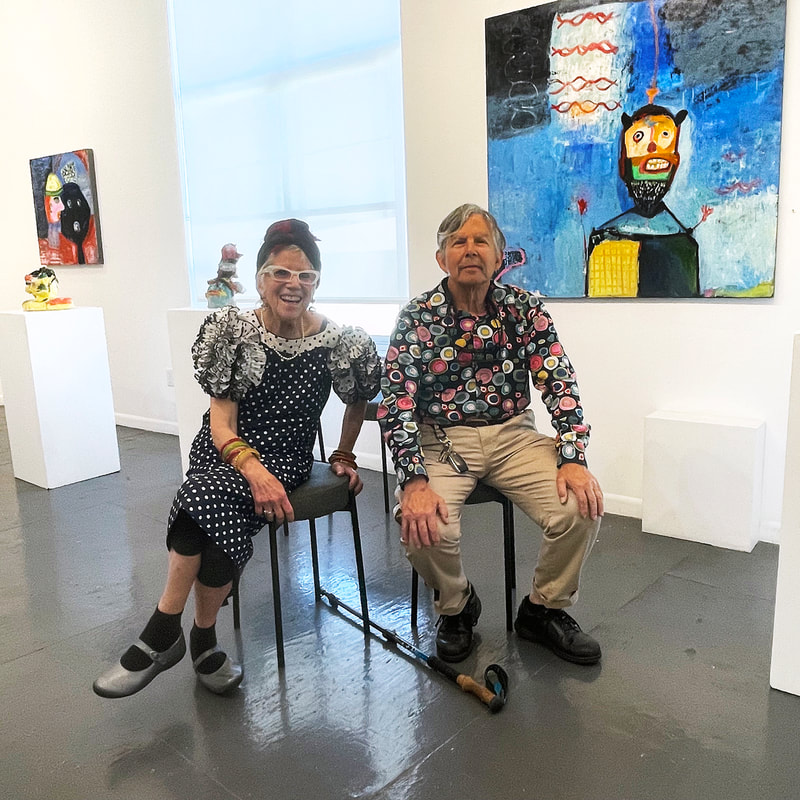 two people seated on stools in an art gallery