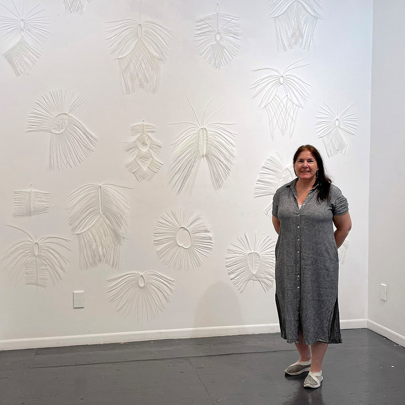 Zip tie artwork installed on a wall with woman standing in front