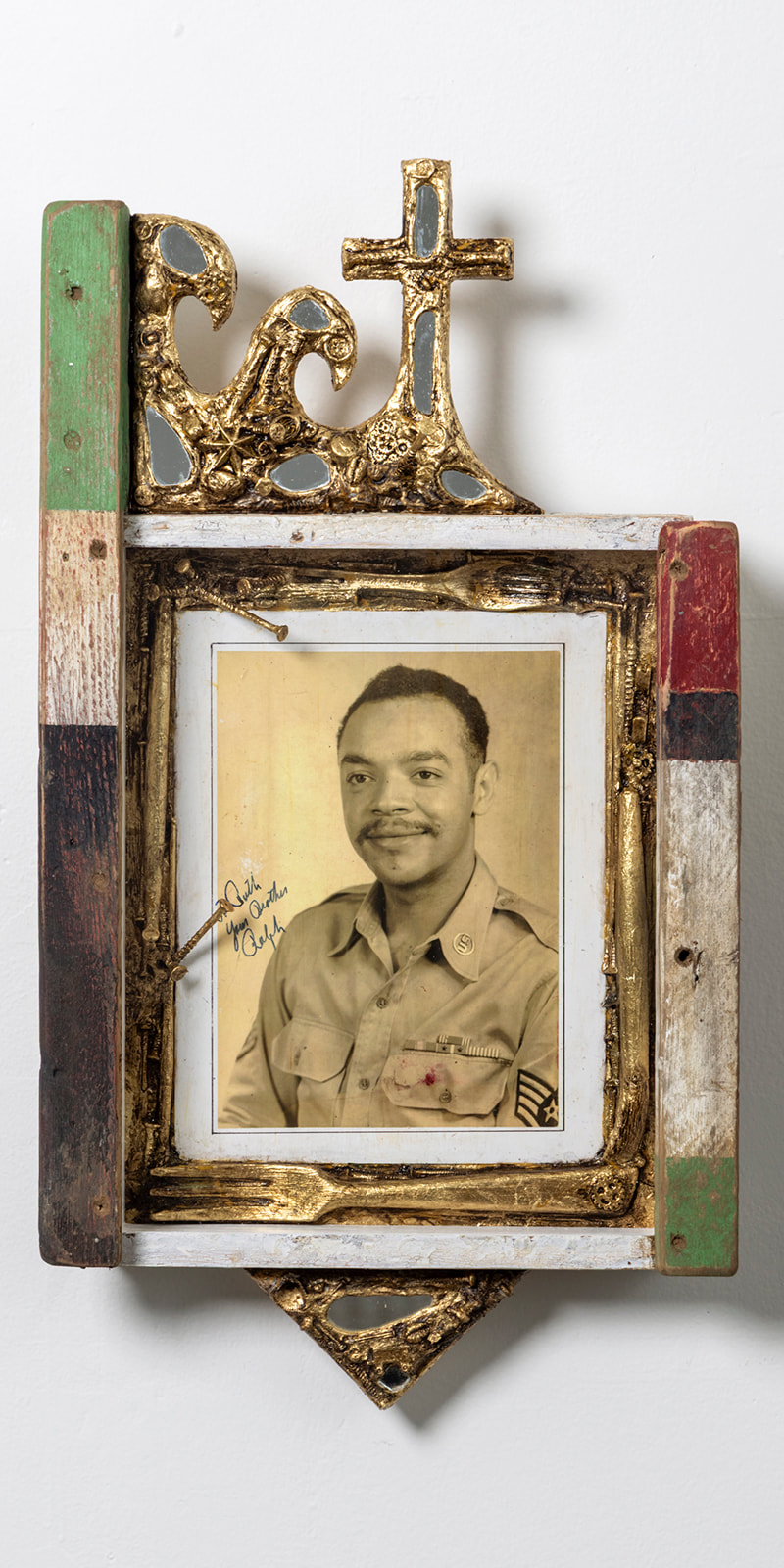 photo portrait of a Black soldier in a frame bordered by gold leafed utensils and with a mirrored cross on top
